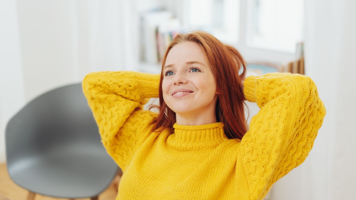 6 Ways To Lower Expenses on a Middle Class Budget While Living a Luxury Lifestyle 3 Thoughtful relaxed young woman daydreaming sitting back with her hands behind her head looking up with a smile.
