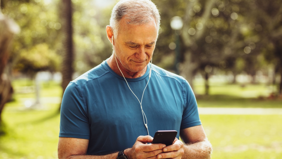 Senior man in fitness wear checking his mobile phone during workout.