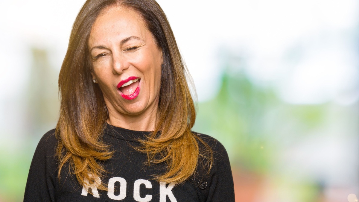 Beautiful middle age woman wearing rock and roll sweater winking looking at the camera with sexy expression, cheerful and happy face.