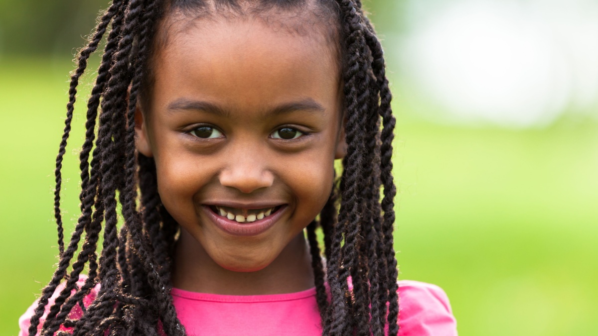 Outdoor close up portrait of a cute young black girl smiling.