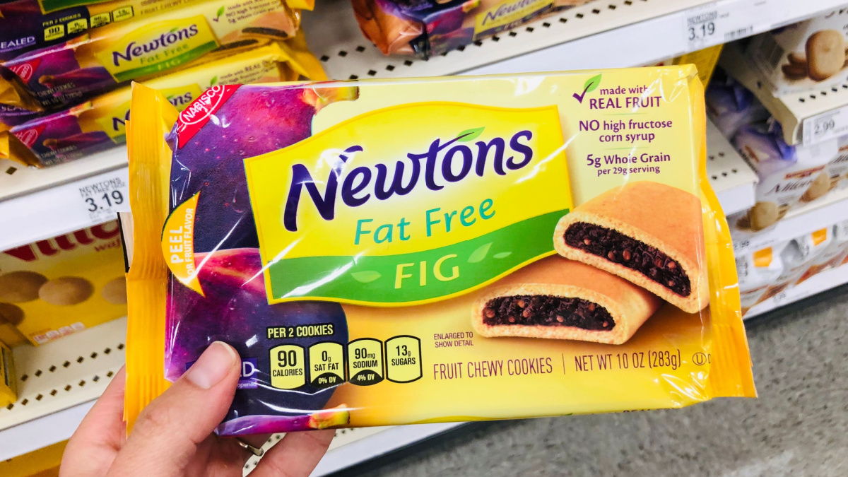 Caucasian hand holds up a package of Nabisco Fig Newton Fat Free chewy cookies while shopping at a grocery store