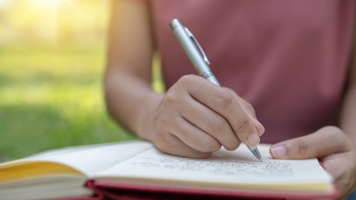 poem, poetry and knowledge education concept, close up sitting writing on notebook in park