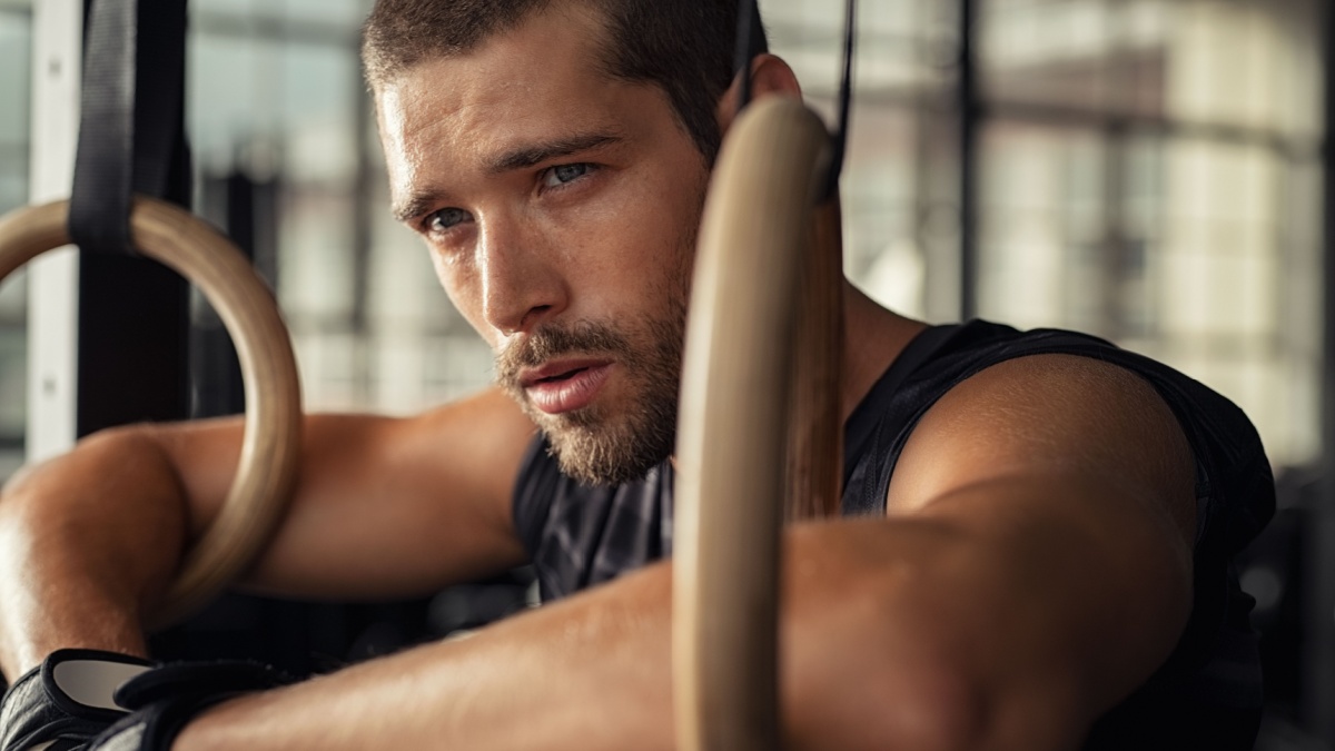 Closeup of young man resting after gymnastic ring exercise at crossfit gym.