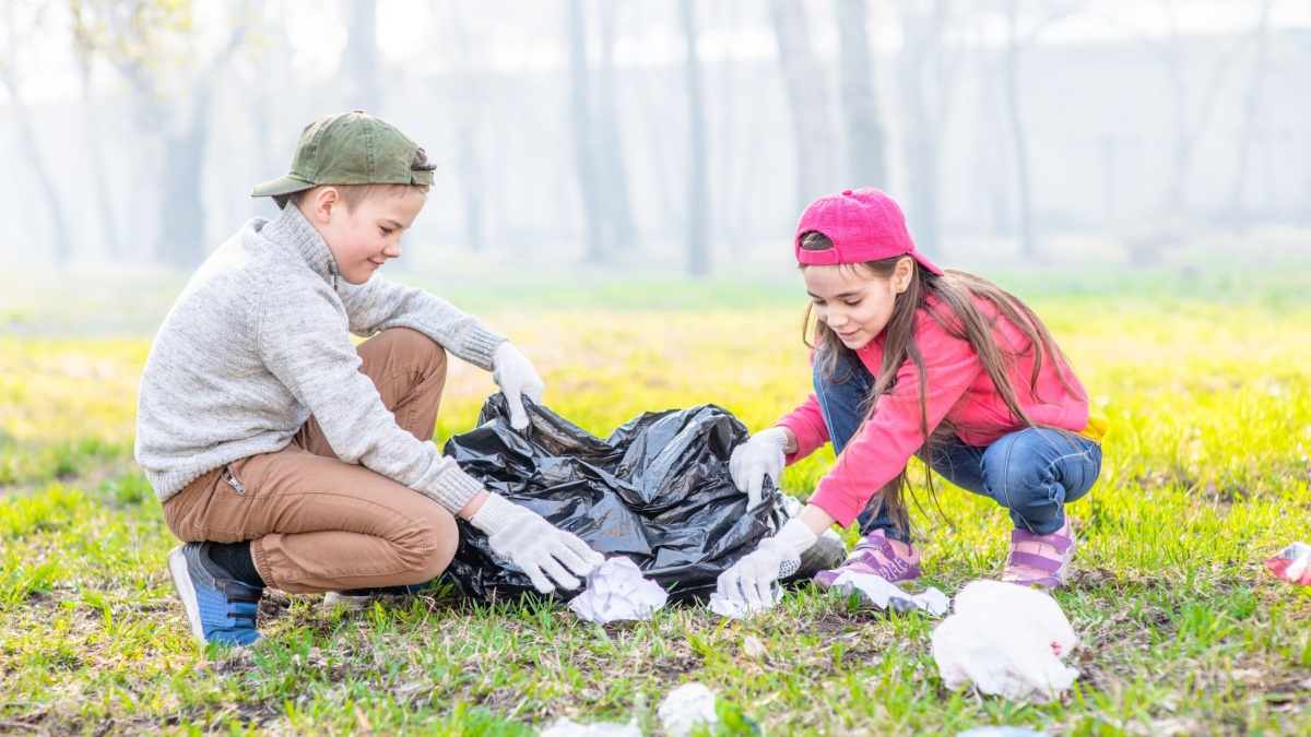 Young volunteers with garbage bags cleaning up garbage outdoors. Volunteer and ecology concept