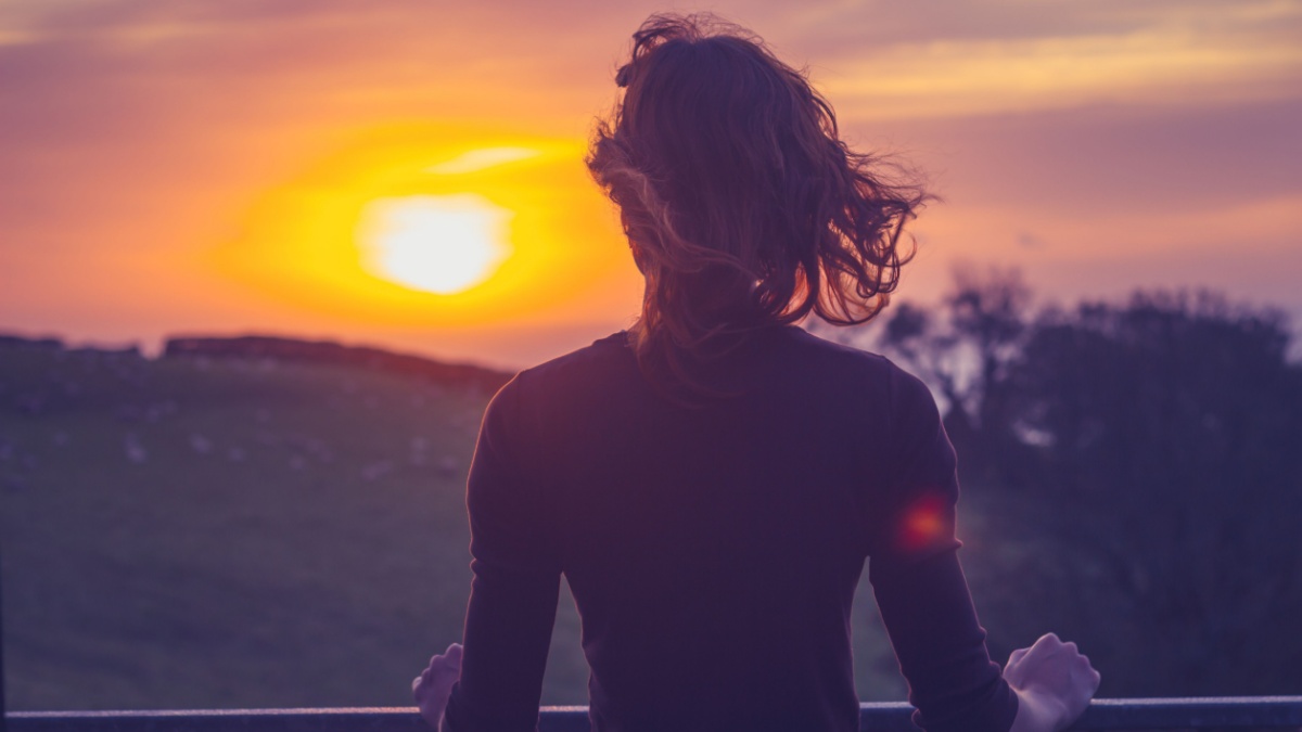 Woman admiring sunset from her balcony.