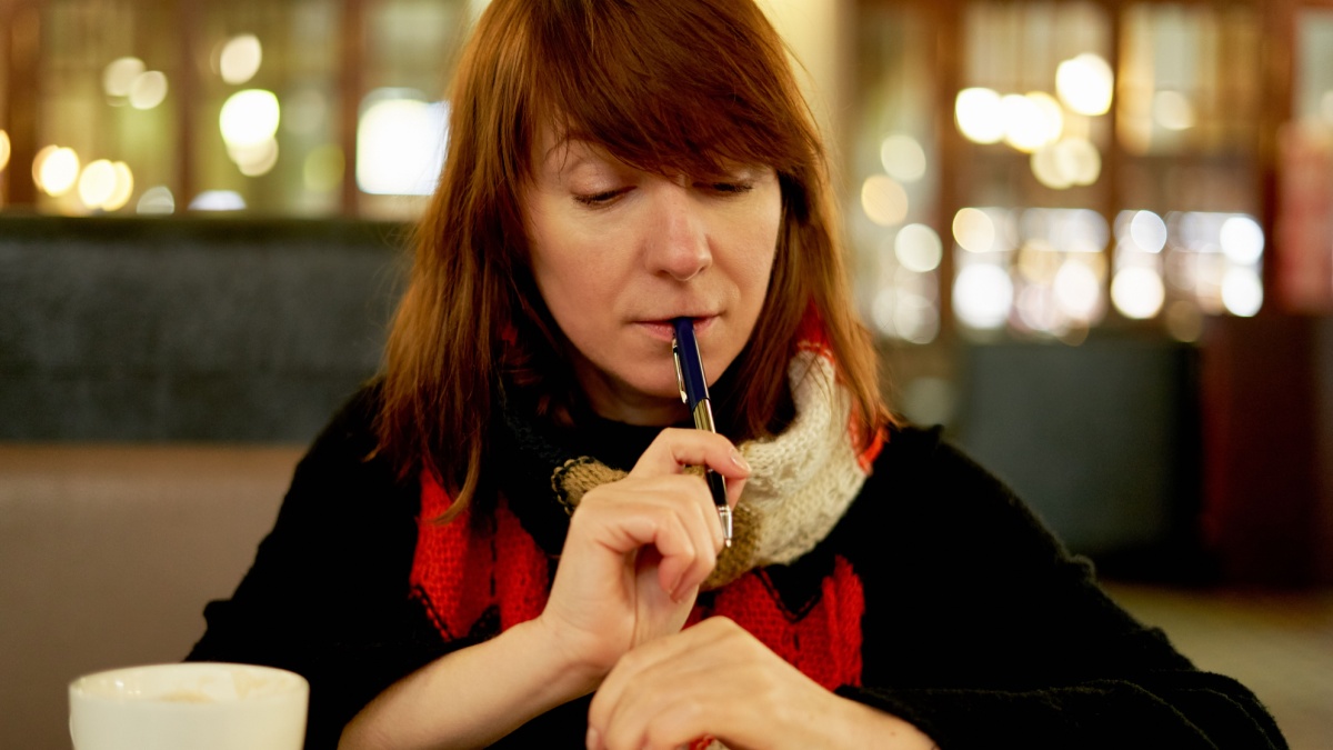 Woman in cafe writes in diary, bullet journal. Slow life, social detox, freelance, planning, self-immersion, being single concept. Middle-aged female think about morning pages in cafe.