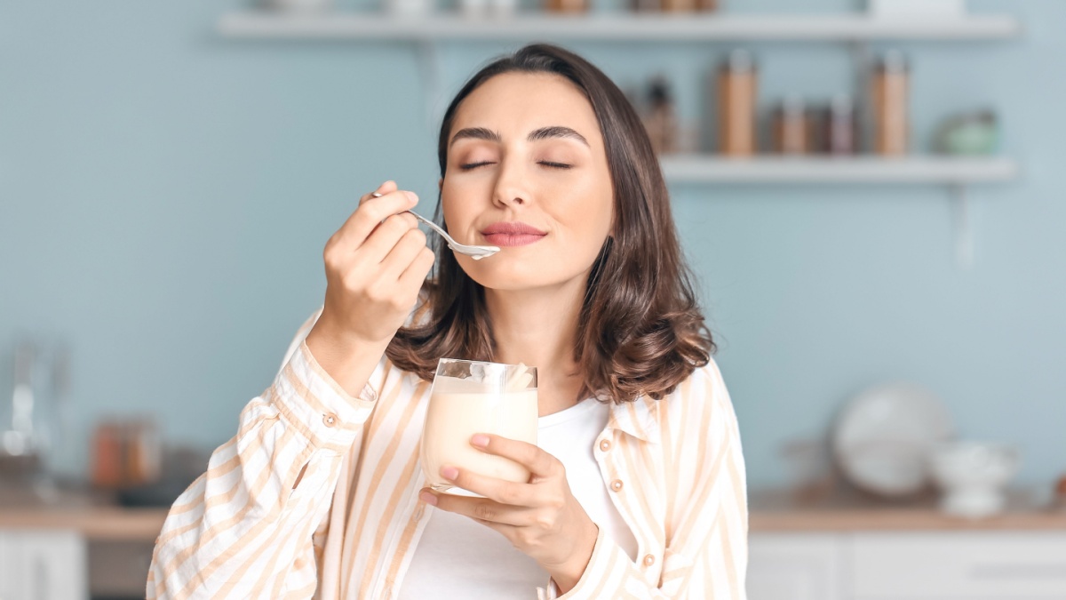 Young woman eating tasty yogurt at home.