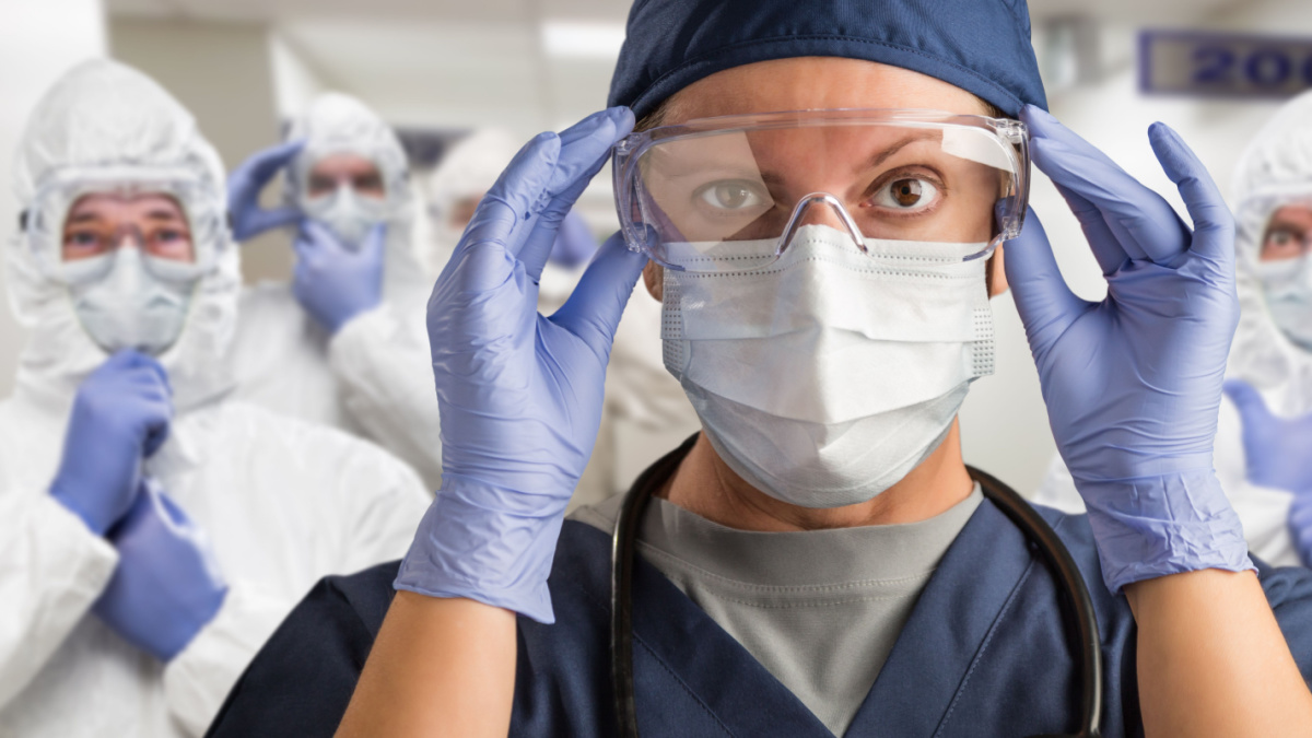 Team of Female and Male Doctors or Nurses Wearing Personal Protective Equiment In Hospital Hallway.