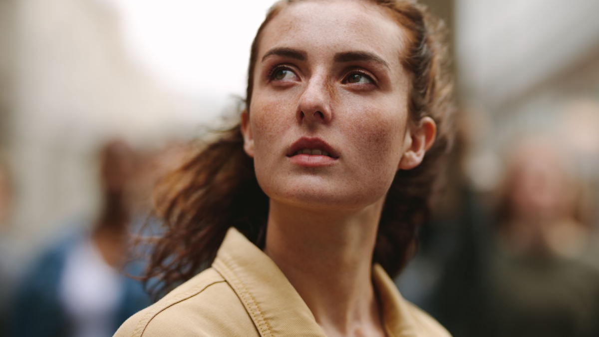 Close-up of woman activist looking away with group of protestors in background.