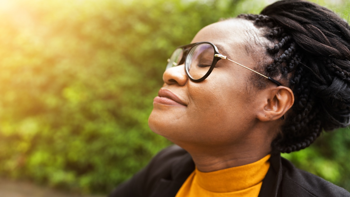 African Woman Breathing Clean Air In Nature With Eyes Closed.