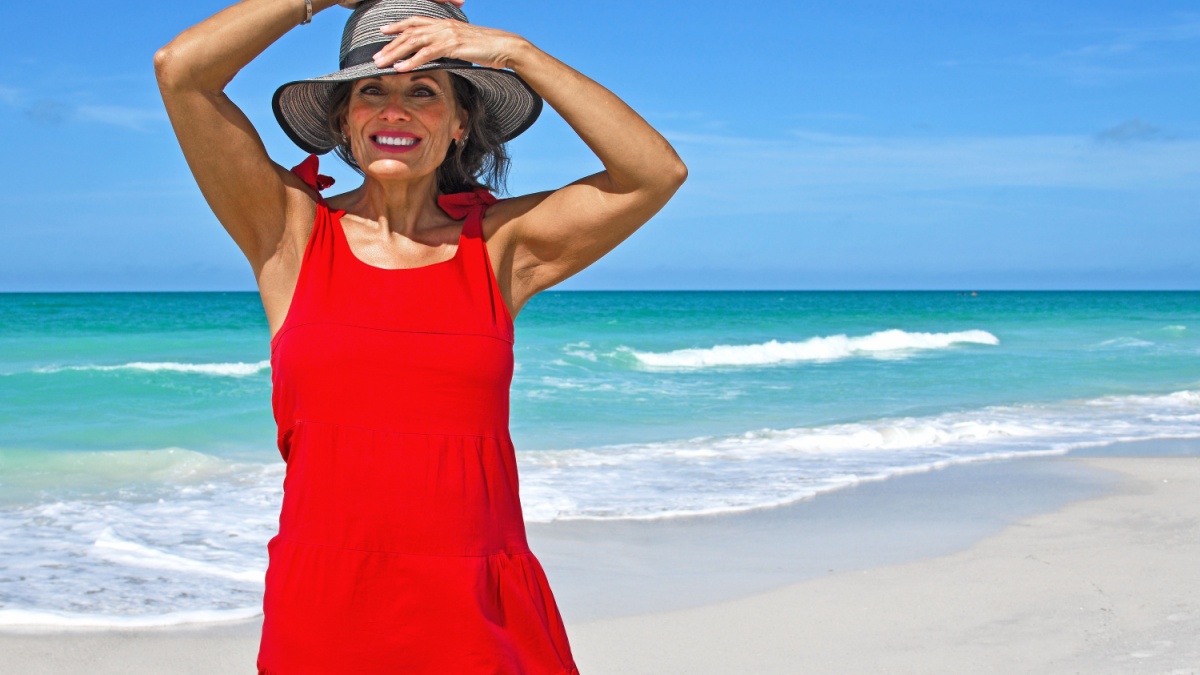 Beautiful Mature Woman Wearing a Red Summer Dress on the Beach.