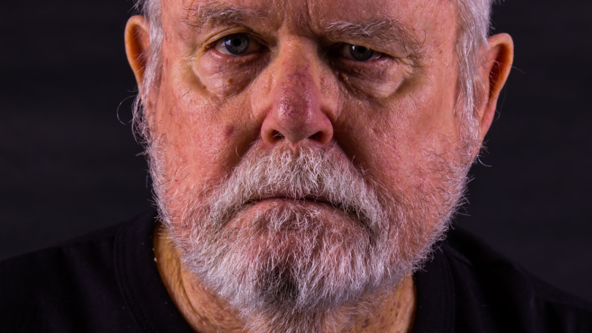 Old Senior Man With Scraggly Beard Looking At Camera.