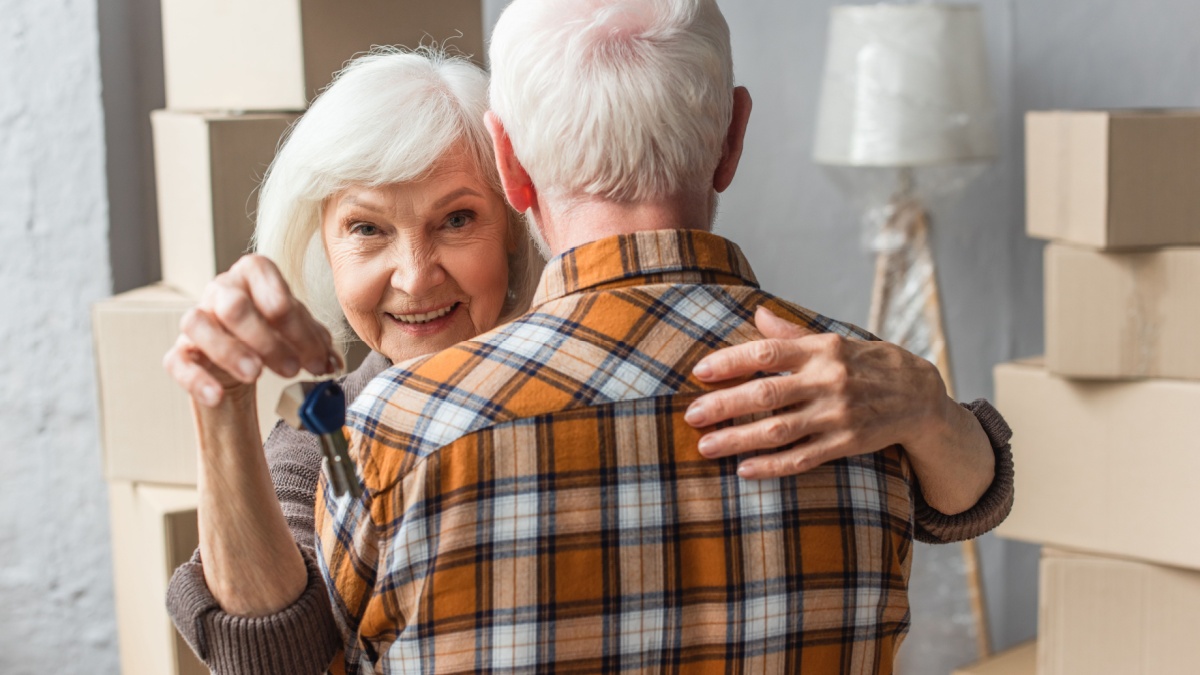 smiling senior woman holding keys and hugging husband, moving concept.