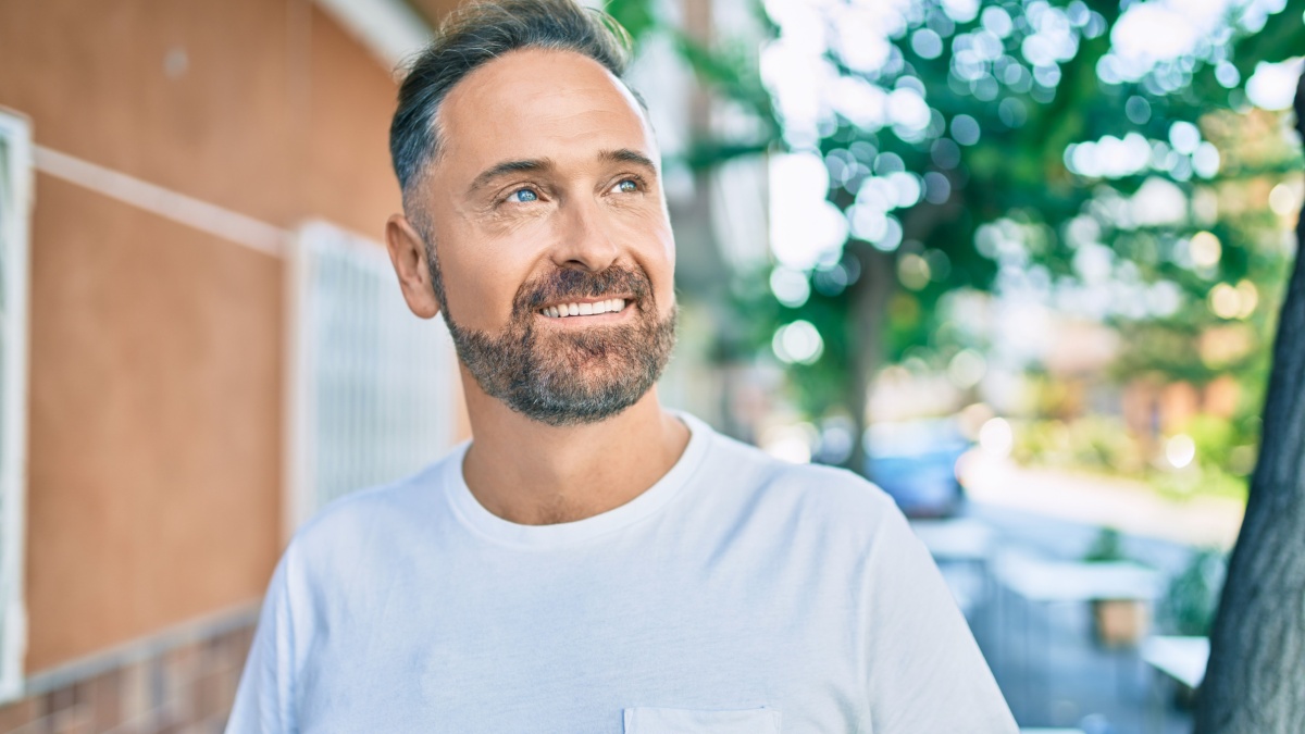 Middle age handsome man smiling happy looking to the side at the city.