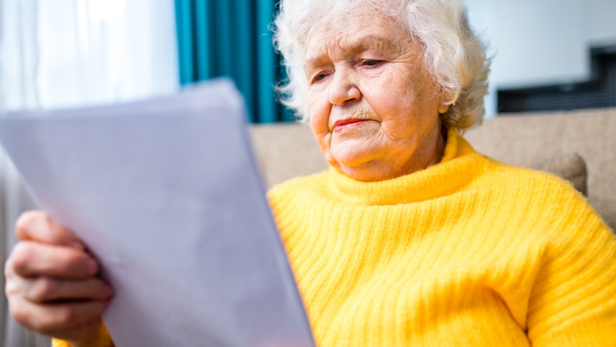 old senior woman hands wrinkled skin close up on knees.