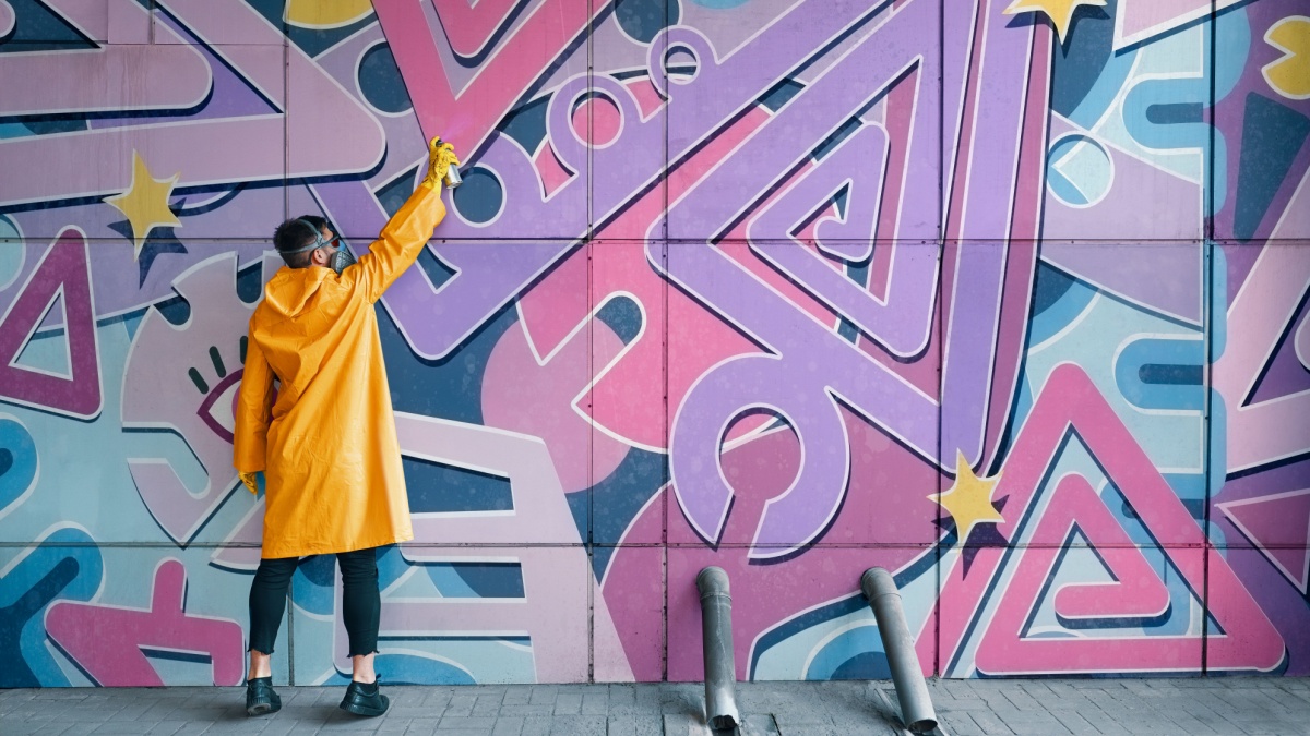 Street artist painting colorful graffiti on wall. Modern urban art concept