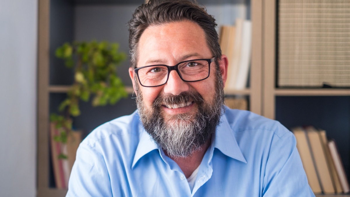 Portrait of one young and happy cheerful man smiling looking at the camera having fun. Headshot of male person working at home in the office.