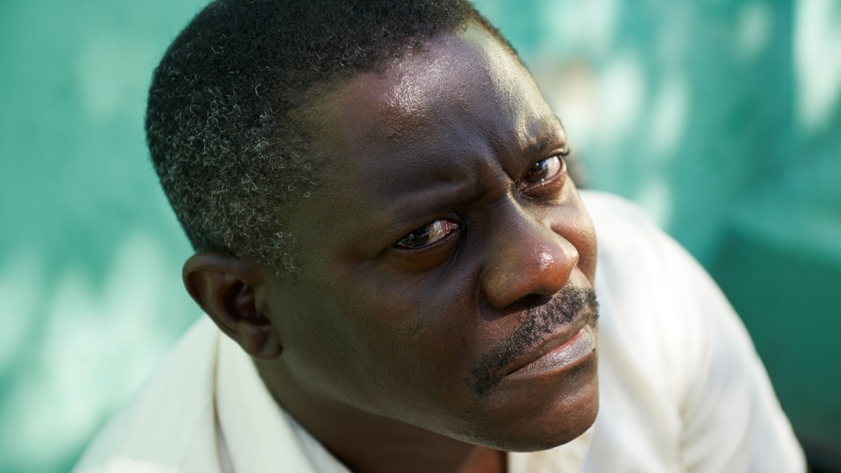 Portrait of mid aged african american man sitting in park and looking at camera with sad expression.