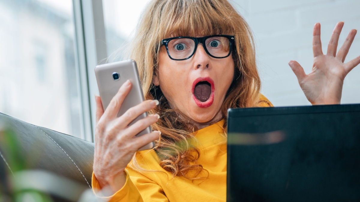 amazed woman with mobile phone and computer at home.