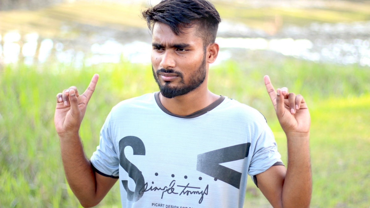 Bangladesh, Rangpur- July 12, 2021. A young man two hands up side and show his finger. his behind background blur.