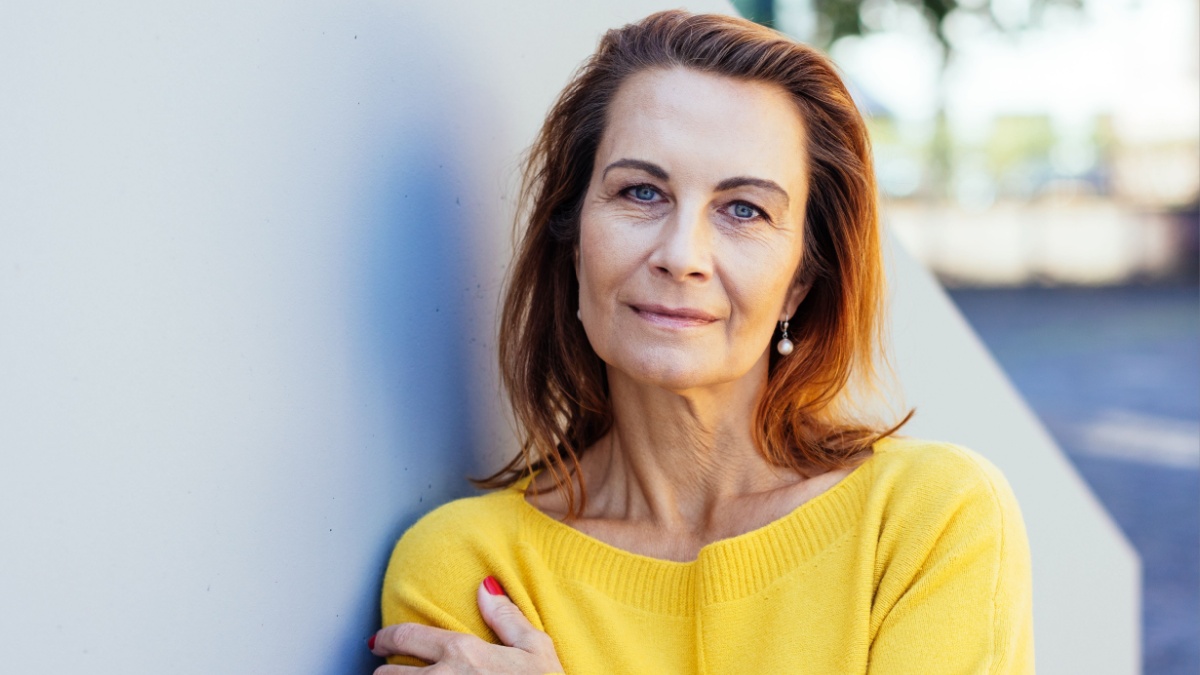 Pensive woman looking earnestly at the camera with a serious wistful expression while hugging herself on the arm in a deserted street in the city.