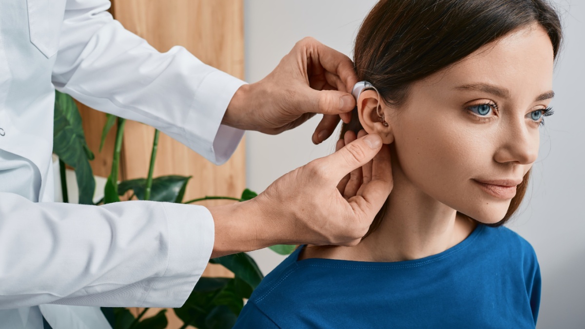 20 Essential Habits for a Longer, Healthier Life 11 Installation hearing aid on woman's ear at hearing clinic, close-up, side view. Deafness treatment, hearing solutions