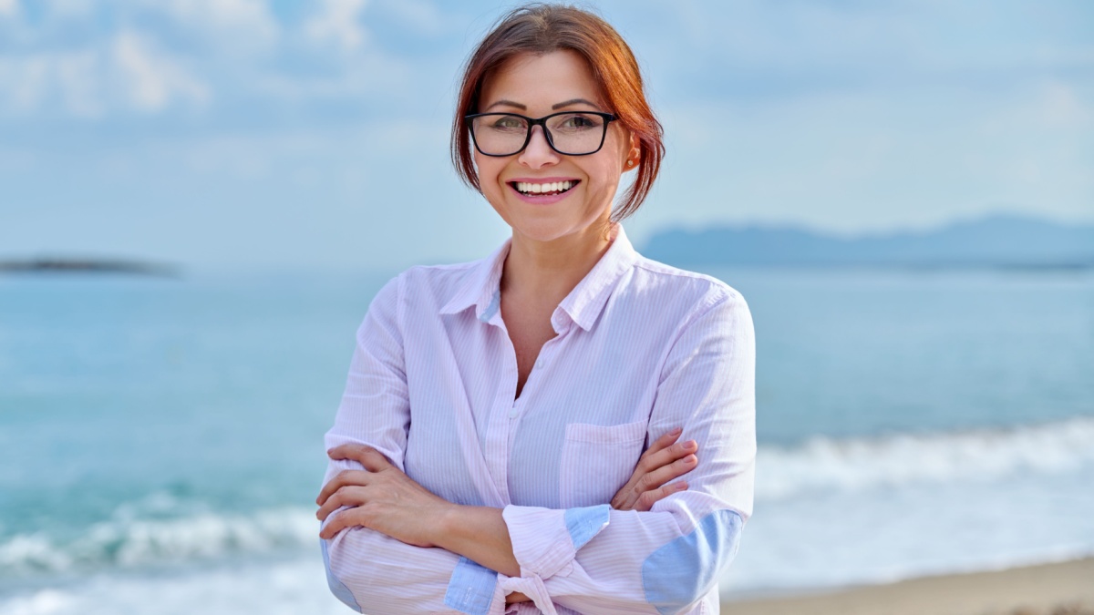 Outdoor portrait of mature smiling woman on sea vacation.
