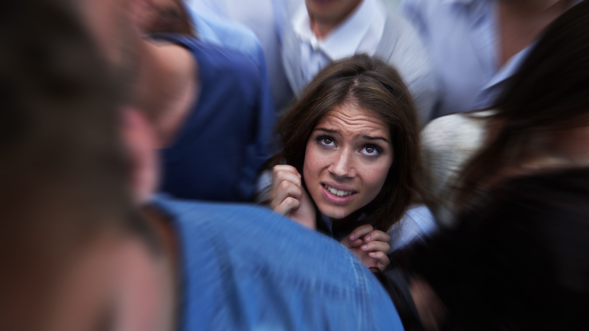 Drowning in people. Shot of a fearful young woman feeling trapped by the crowd.