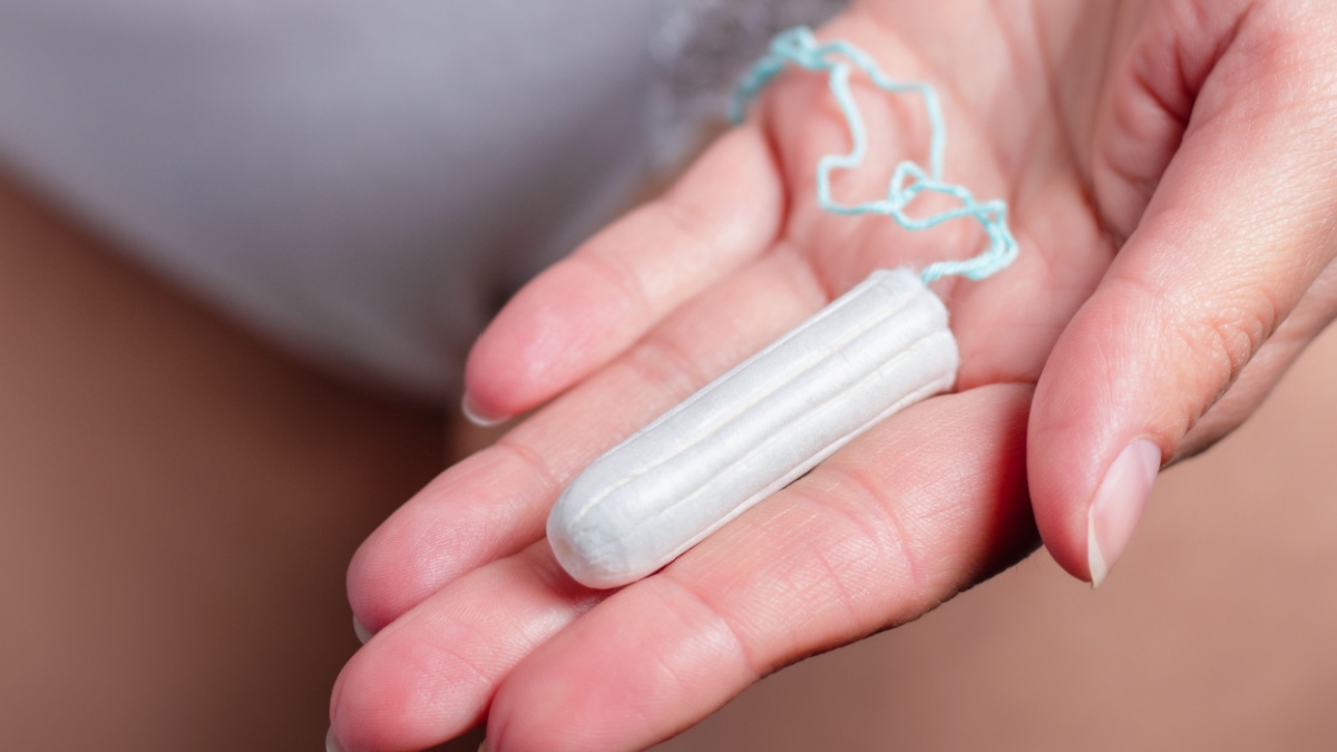 Girl in underwear holding menstruation tampon in hand - women's menstrual cramps. Menstruation, means of protection