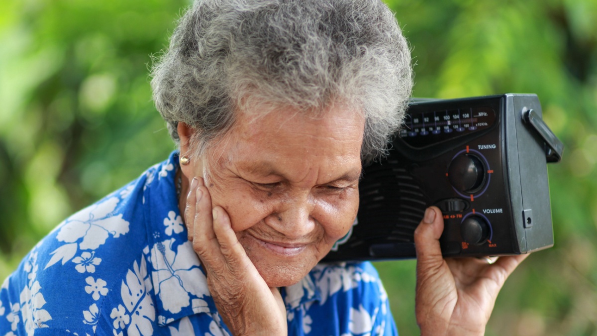 Old Woman Listening To Music With A Vintage Radio, outdoor.