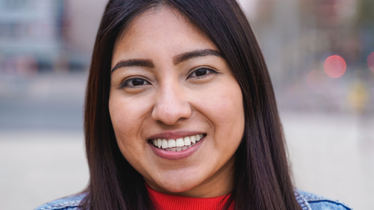 Indigenous young woman smiling while looking at camera outdoor - Focus on face.