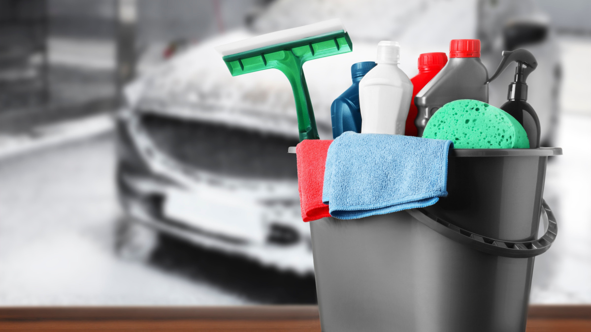 Bucket with cleaning supplies on wooden surface at car wash.