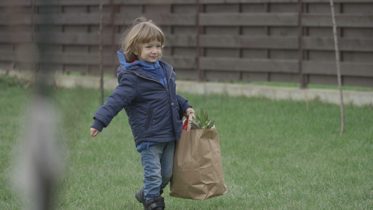 Funny little child holding big shopping bag with groceries , happy to help