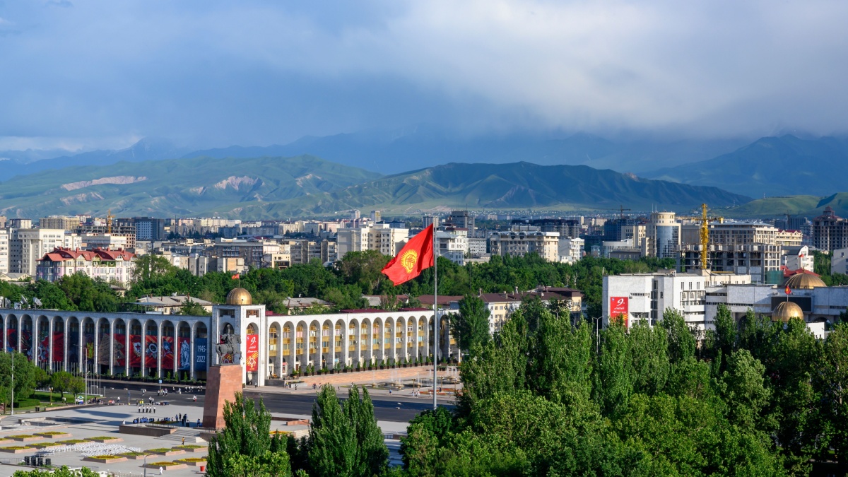 BISHKEK, KYRGYZSTAN - MAY, 17, 2022: Panorama of Bishkek, the capital of Kyrgyzstan, with a central square, a monument to Manas, a national flag, against the background of mountains covered with clouds.