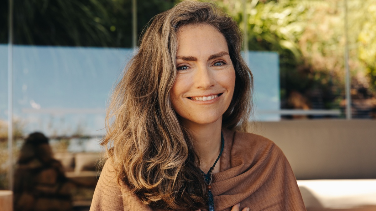 Senior woman smiling at the camera while wearing a crystal necklace.
