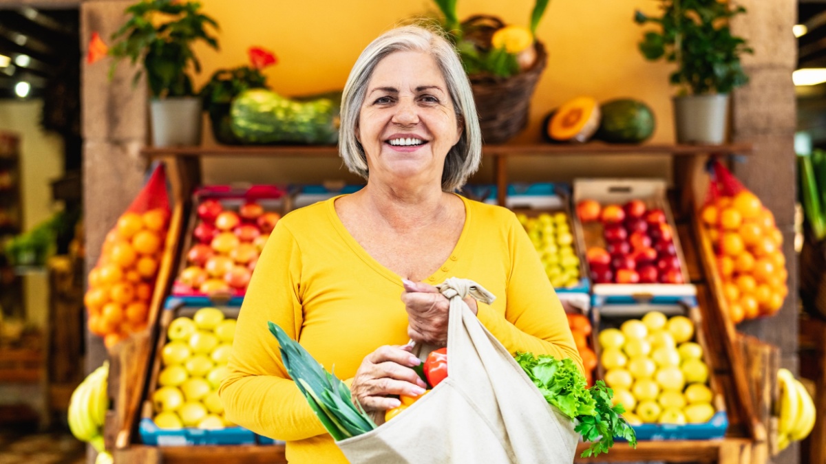 Happy senior woman buying fruits and vegetables at the market - Shopping food concept.