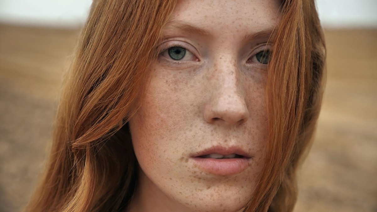 Close up Natural Beauty Ginger Woman is standing on golden Field happily, enjoying Nature. Amazing Woman with long Red Hair, smiling Charmingly.