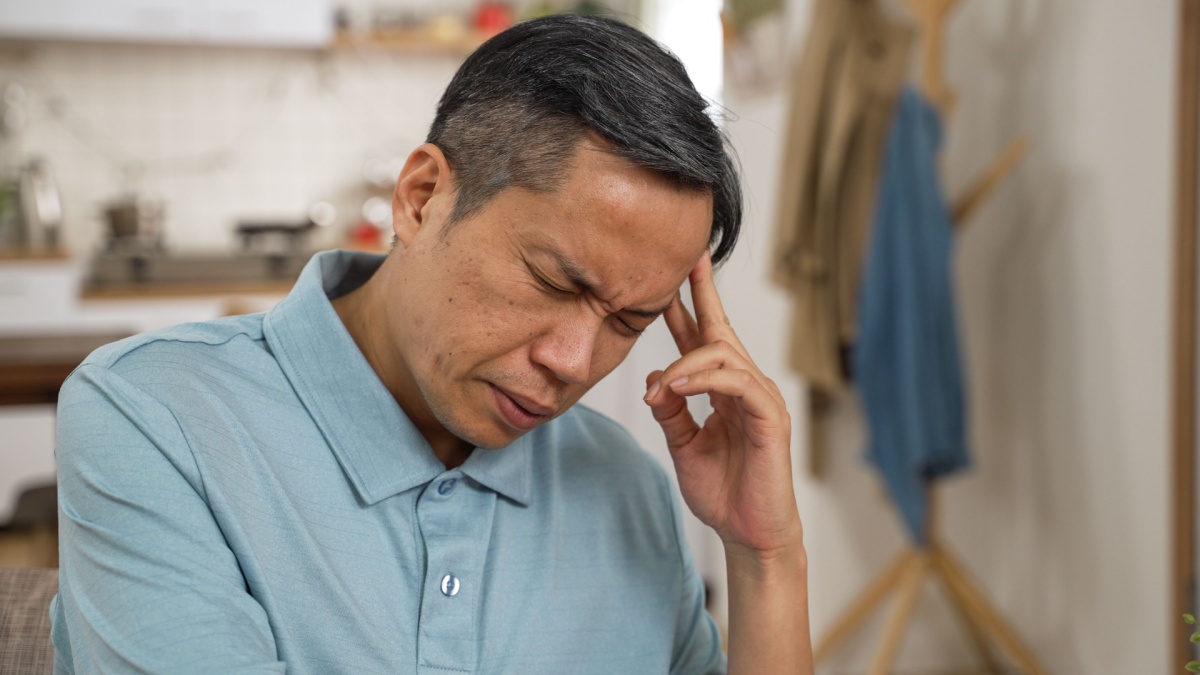 closeup of stressed asian elderly male worrying about problem alone at home. he props his head while thinking hard for solutions.