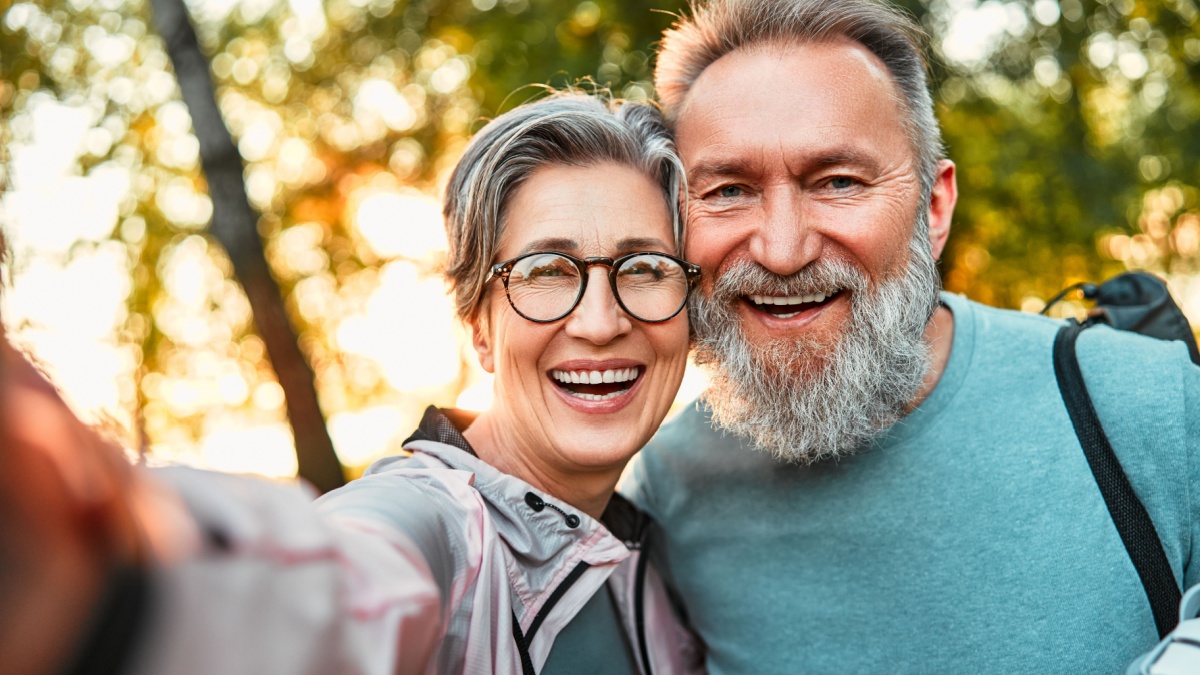 Wonderful sincere cheerful couple of gray haired mature smiling people taking selfie portrait on phone.