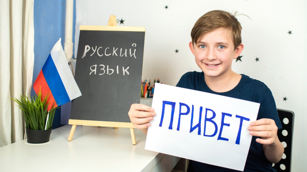 An 11-year-old boy is studying a foreign Russian language. a child holds a piece of paper with the word