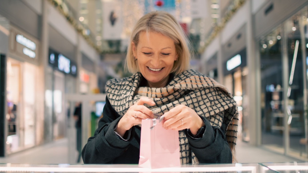 mature blonde woman buys new year gift in shopping mall.