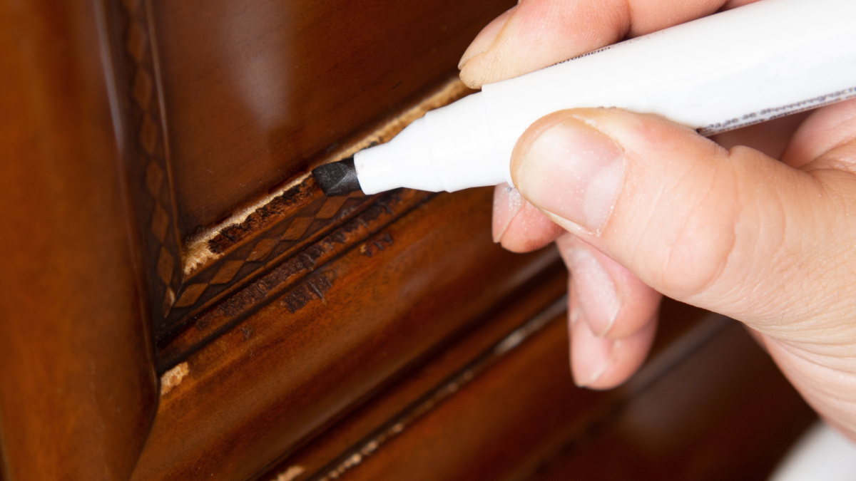 Furniture marker, restoration of wooden furniture. the master fixes a scratch on the facade
