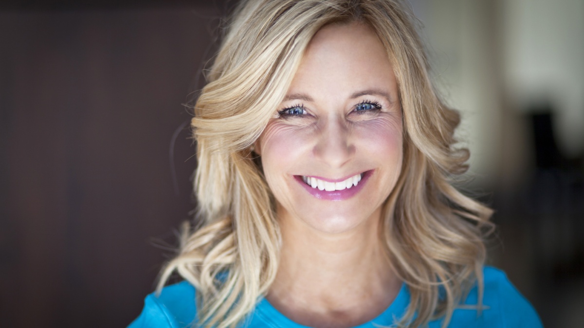Mature blond woman smiles at camera.