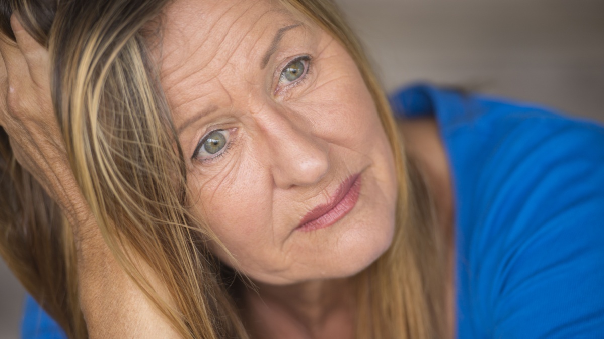 Portrait attractive mature woman with sad, lonely, depressed and stressed facial expression, worried, blurred background.