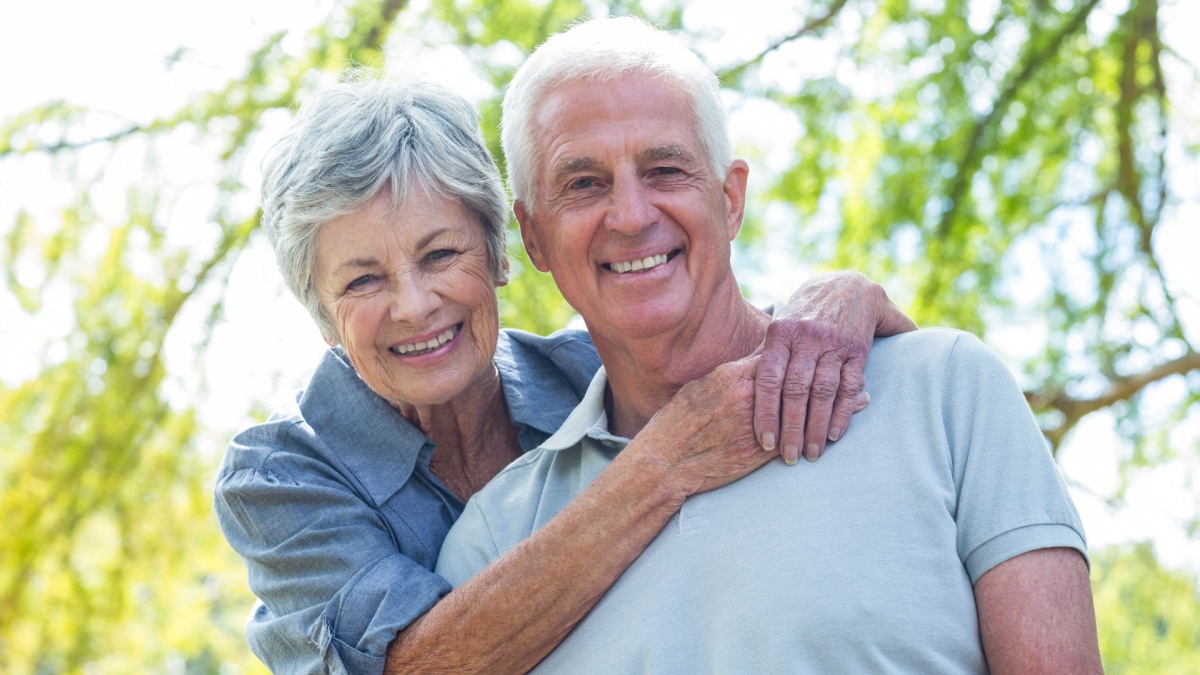 Happy old couple smiling in a park on a sunny day.