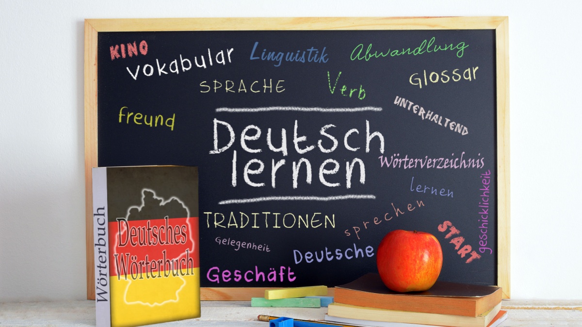 Blackboard in a German language classroom with the message LEARN GERMAN and some other linguistic words.