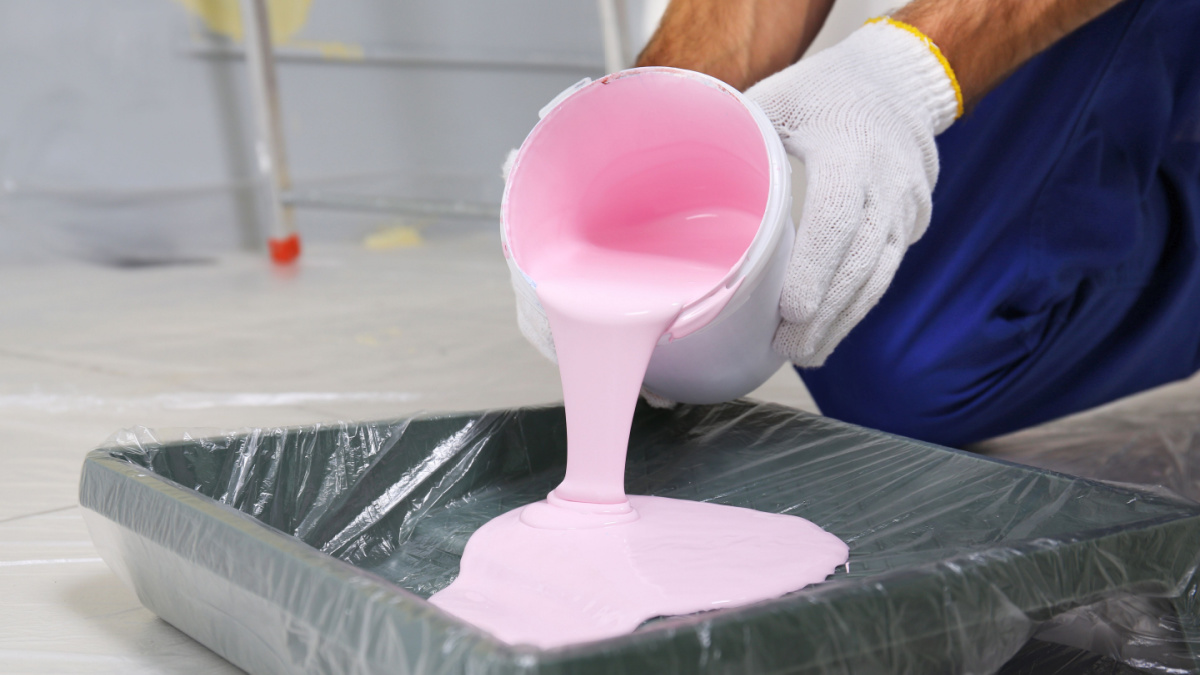 Worker pouring paint for repair into tray, closeup