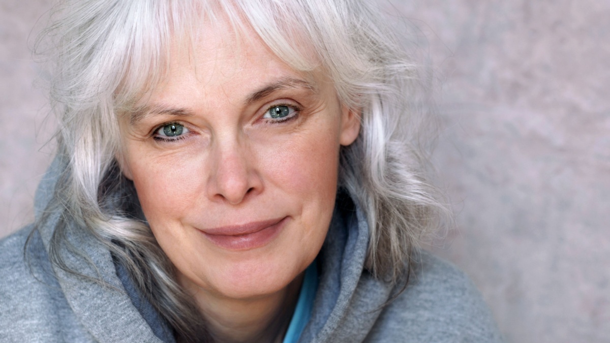 Casual portrait of happy mature woman with natural white hair and minimal makeup.