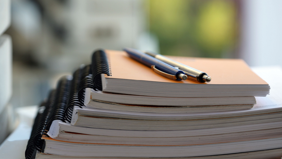 6 Things Frugal People Never Buy At The Dollar Store 3 Stack of notebooks with pens on the top.
