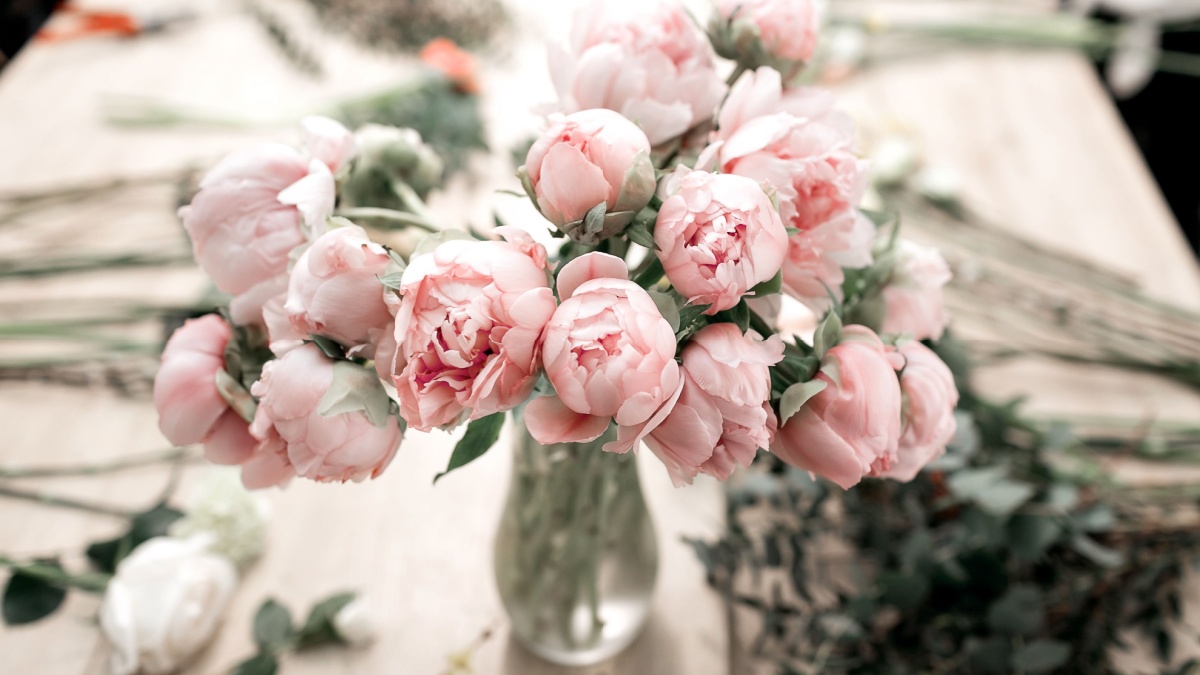 Pink peonies in vase on wooden floor and bokeh background - retro styled photo. soft focus.
